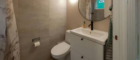 A bathroom with a toilet, sink, and mirror.