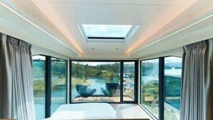 Un dormitorio moderno con tragaluces, ventanas amplias y vista a un lago.