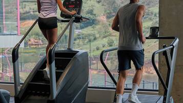 Dos personas usando cintas de correr en un gimnasio con grandes ventanales que dan a un paisaje montañoso.