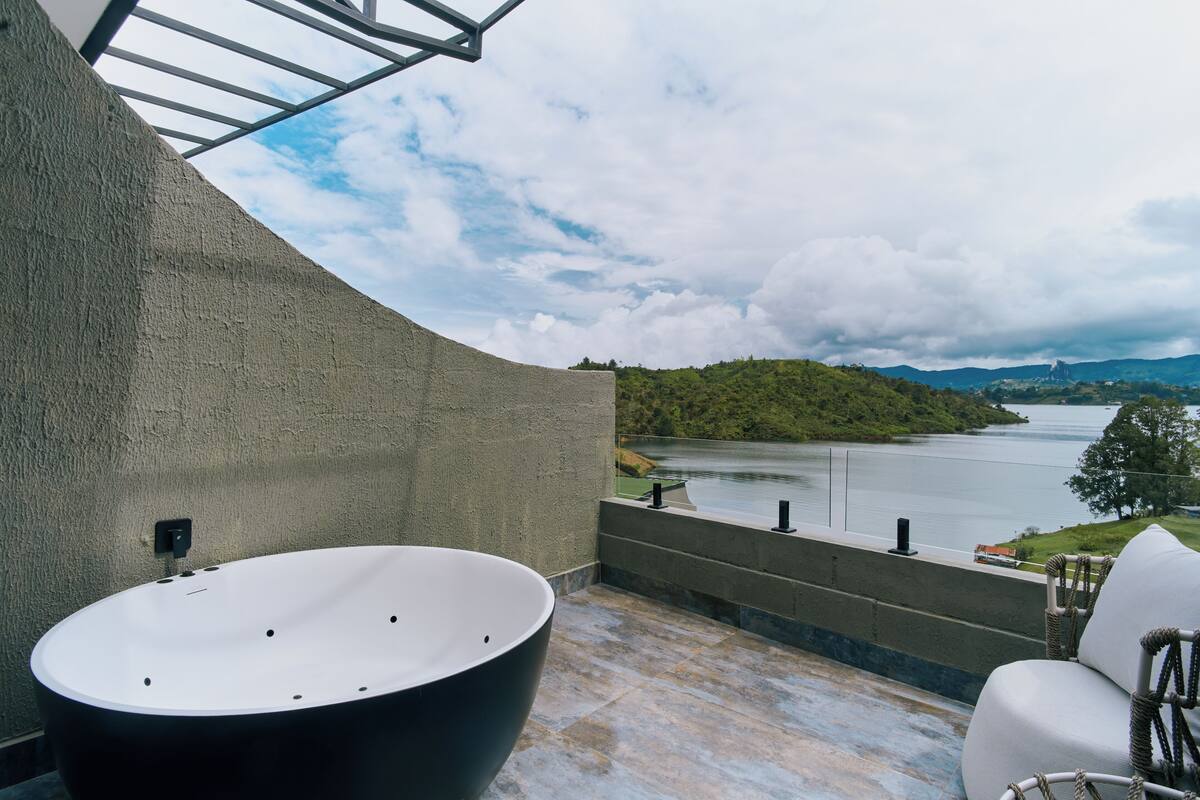 A modern bathroom with a large bathtub, a view of a lake, and a seating area with a view.
