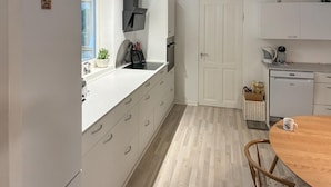 Una cucina moderna con mobili bianchi, un tavolo da pranzo in legno e un frigorifero bianco.
