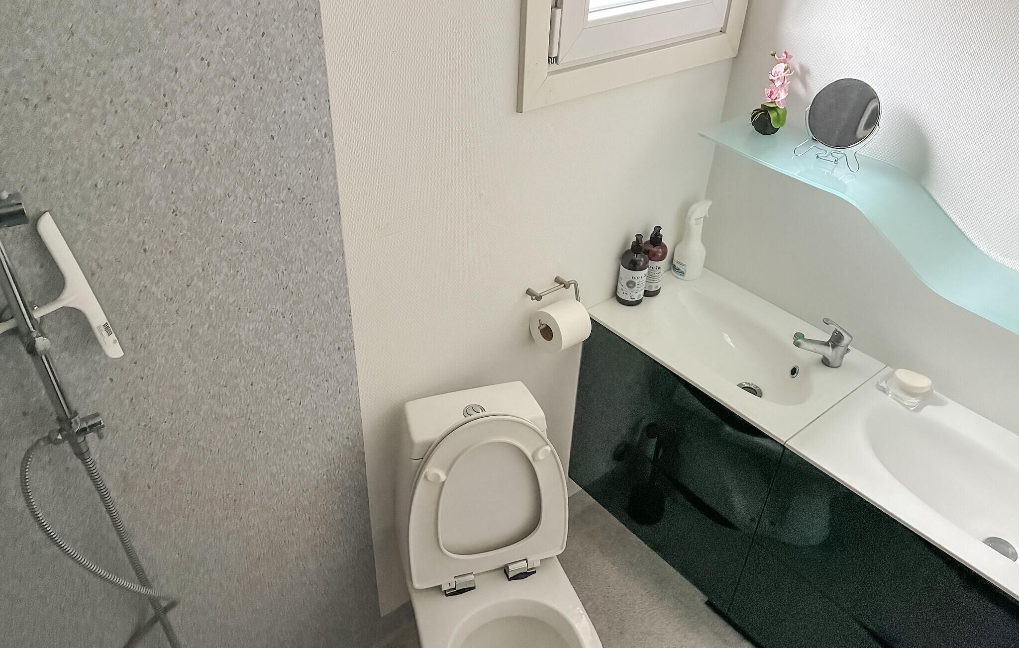 Un baño con inodoro, lavamanos, espejo y ducha.