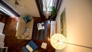 Un saló modern amb un sofà, un tamboret blau i una taula de centre. Hi ha una planta en test i un quadre a la paret.