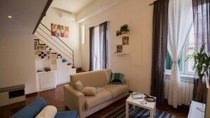 Un saló amb un sofà, una taula de centre i una escala que condueix a un pis superior.