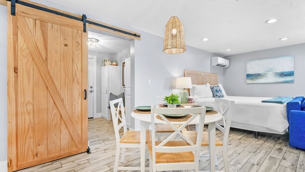 Un interior moderno con comedor, un dormitorio con cama y vistas, y una puerta corredera.