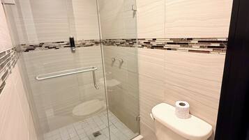 Un baño moderno con ducha de vidrio, inodoro y bidé.