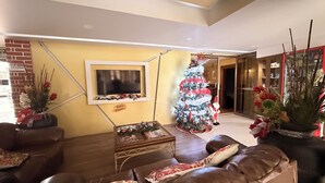 Una sala de estar con un árbol de Navidad, sofás de cuero, un televisor de pantalla plana y una chimenea.