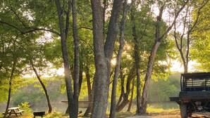 Un terrain de camping avec un chemin de gravier, une table de pique-nique et un véhicule.