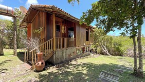 A rustic wooden cabin with a porch, a satellite dish, and a large terracotta pot. - Bangal Beira da Lagoa com Acesso Direto Praia (Prado)