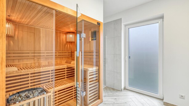 Ein Saunaraum mit Holzbänken und einer Glastür.