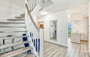 A modern interior with a wooden staircase, a mirrored wall, and a kitchen area with a view of the outdoors. - Lovely home in Wurster Nordseeküste with sauna (Wurster Nordseeküste)