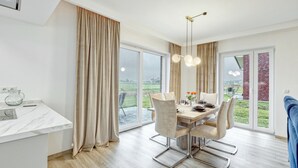 Ein moderner Essbereich mit einem Holztisch, vier Stühlen und einem großen Fenster mit Blick ins Freie.