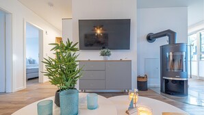 Una sala de estar moderna con un sofá, un televisor montado en la pared, una chimenea y una planta en maceta.