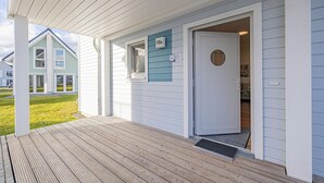 Una casa con un porche de madera, una puerta principal y un buzón.