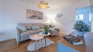 Una sala de estar moderna con un sofá, una mesa de centro, una lámpara y una estantería.