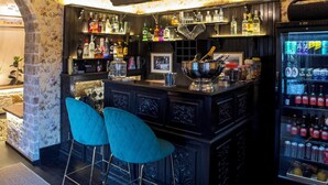 Een bar met houten plafond, barstoelen, een toonbank met flessen en een koelkast.
