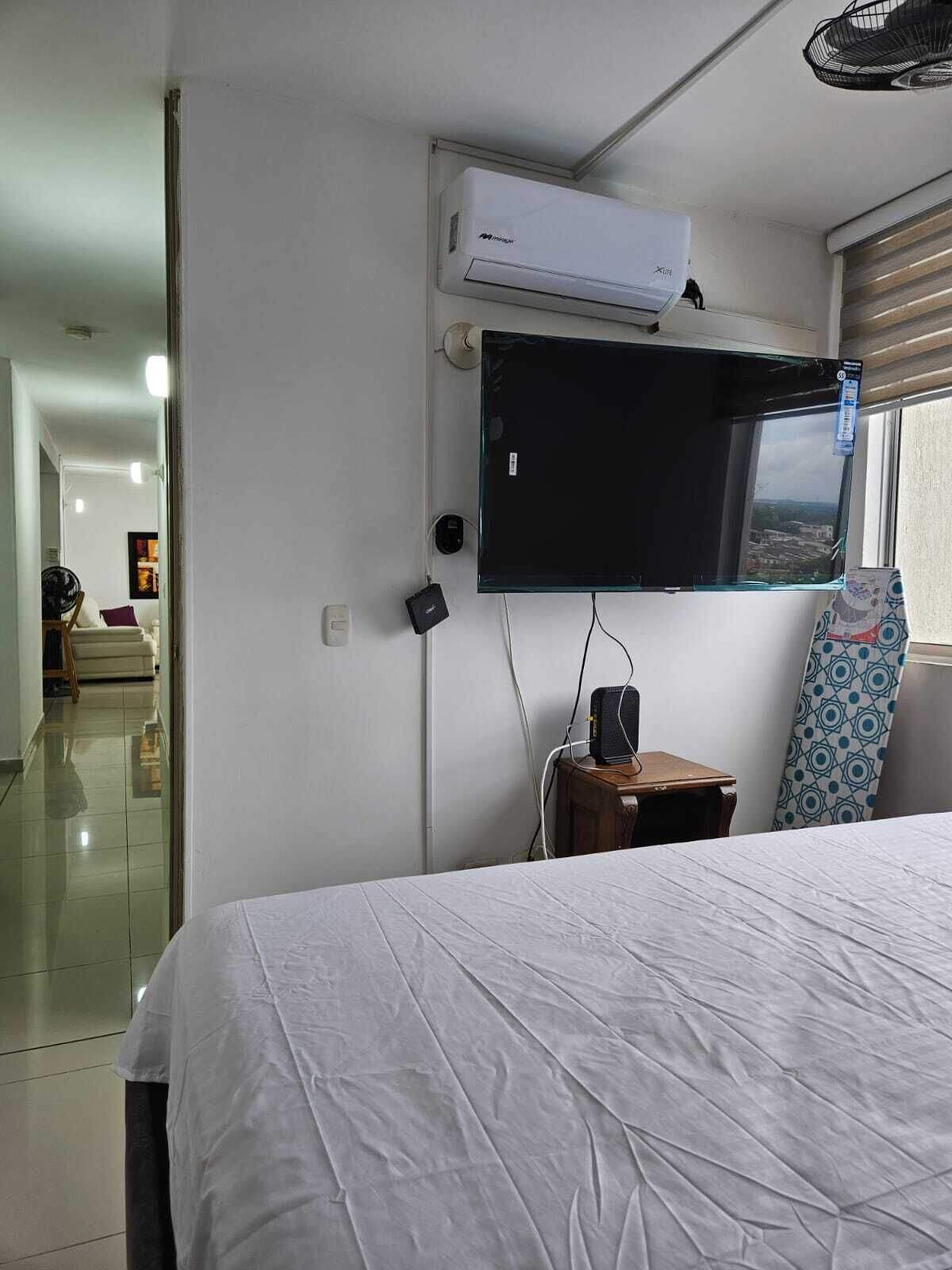Une chambre d’hôtel équipée d’un lit, d’un téléviseur fixé au mur, d’un climatiseur et d’une fenêtre donnant sur un paysage agréable.