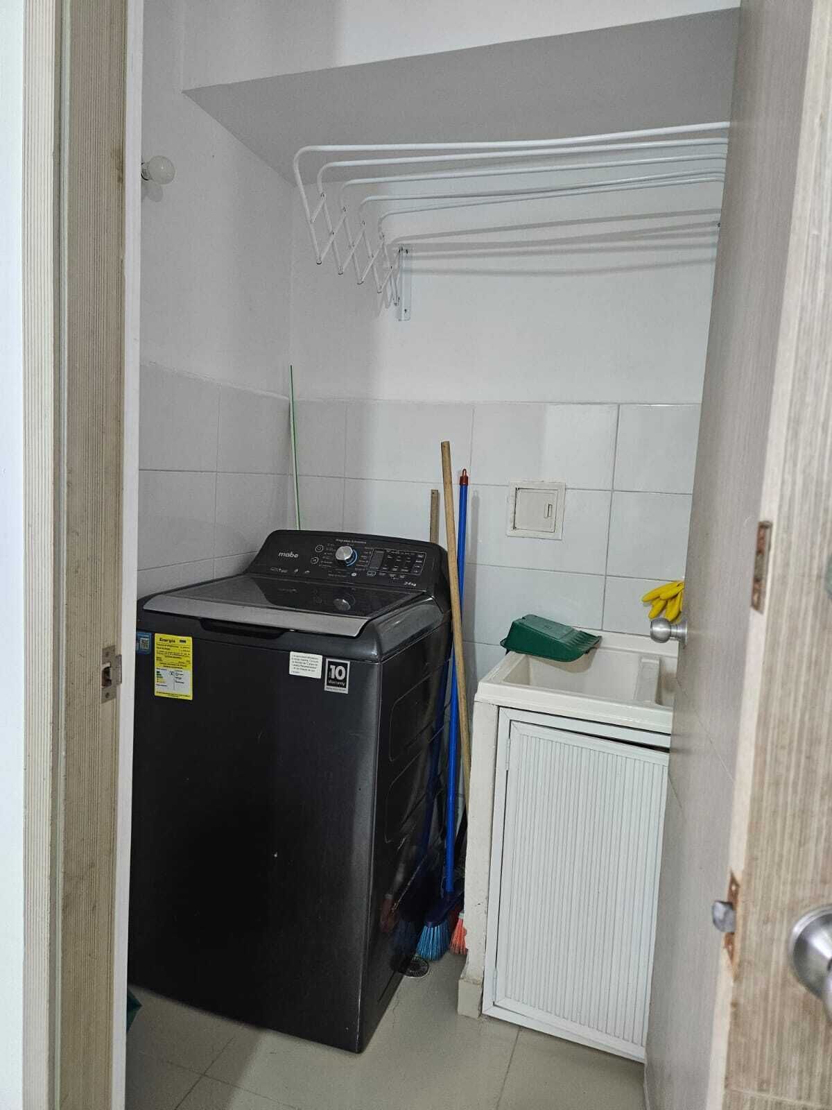 Une petite buanderie équipée d’un lave-linge et d’un sèche-linge à chargement frontal, d’un petit meuble de rangement et d’un porte-serpillière fixé au mur.