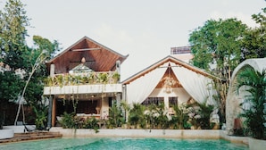 Ein Resort mit Pool, überdachter Außenterrasse und üppiger Bepflanzung.