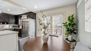 A modern kitchen with dark cabinets, stainless steel appliances, and a dining area with a wooden table and chairs.