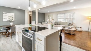 A modern kitchen with a central island, built-in oven, and dining area with a table and chairs.