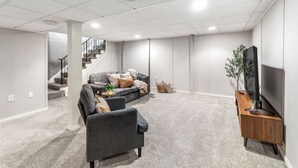 A modern living room with a grey sofa, a dark armchair, and a wooden entertainment unit.