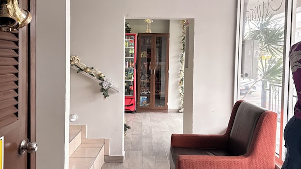 A modern interior with a red sofa, wooden flooring, and a glass door leading to a balcony. - Hotel Mirage Diagonal (Matamoros)