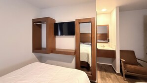 A hotel room with a bed, a chair, a desk with a mirror, and a television mounted on the wall. - Hotel Mirage Diagonal (Matamoros)