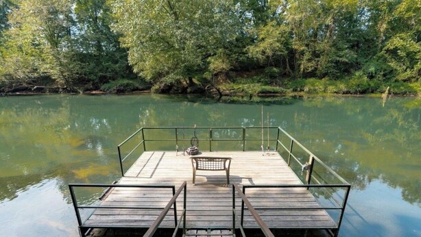 Eine hölzerne Anlegestelle erstreckt sich in einen ruhigen Fluss, umgeben von dichtem Grün.