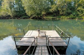 Een houten steiger die zich uitstrekt over een rustige rivier, omringd door weelderige begroeiing.