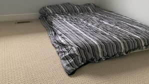 A room with a single bed, a window, and a view of a building outside.