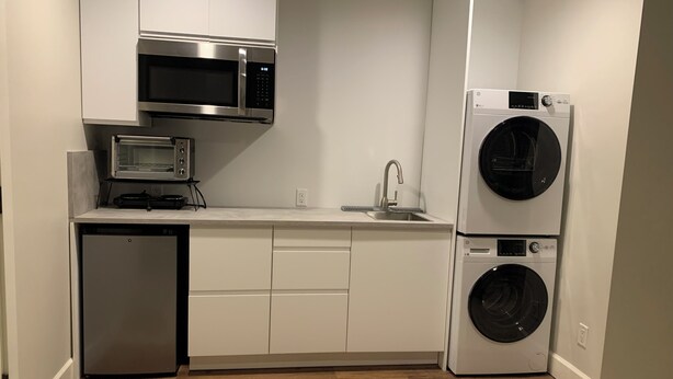 A compact kitchen with a microwave, dishwasher, and stacked washer-dryer unit.