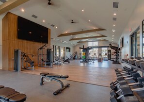 Un gimnasio amplio con diversos equipos de ejercicio, incluyendo cintas de correr, máquinas de pesas y pesas libres.