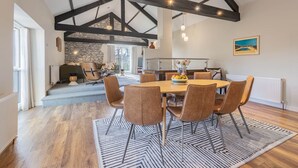 A spacious dining area with a high ceiling, exposed beams, and a large table surrounded by chairs. - Royal Oak Barn - Cartmel, Sleeps 8! (NEW) (Cartmel)
