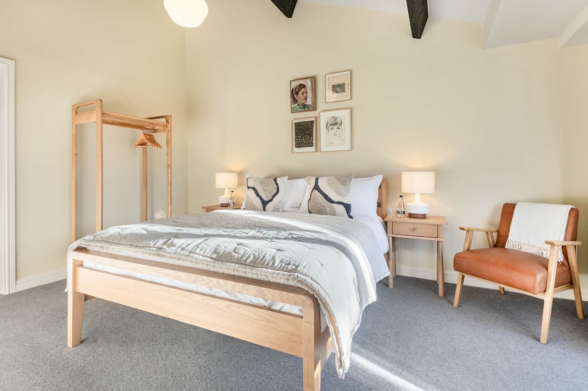 Un dormitorio con cama, mesitas de noche, una silla y decoración en la pared.