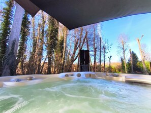 A hot tub with multiple jets, surrounded by tall trees and a clear sky. - Secret travel lodge, Au Calme Absolu (Lindry)