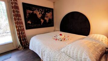 Une chambre avec un grand lit, une carte du monde accrochée au mur et une fenêtre avec des rideaux.