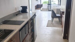 Eine moderne Küche mit einer großen Kochinsel, einem Essbereich mit Tisch und Stühlen sowie Meerblick durch ein großes Fenster.