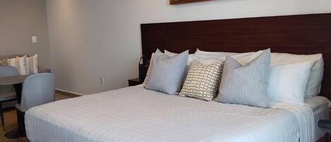 A bedroom with a large bed, a ceiling fan, and a wall-mounted artwork.