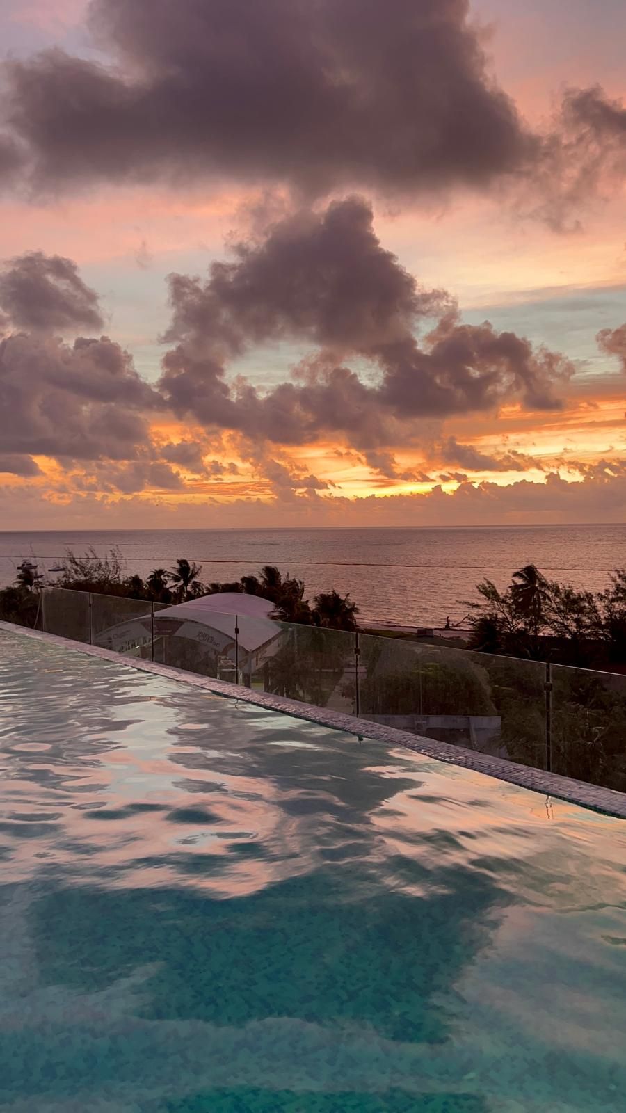 Piscina com vista para o oceano e pôr do sol.