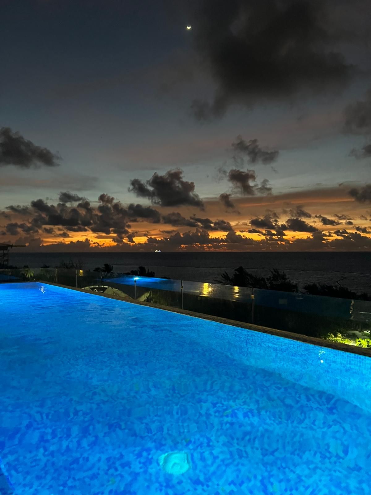 Piscina com vista para o pôr do sol sobre o oceano.