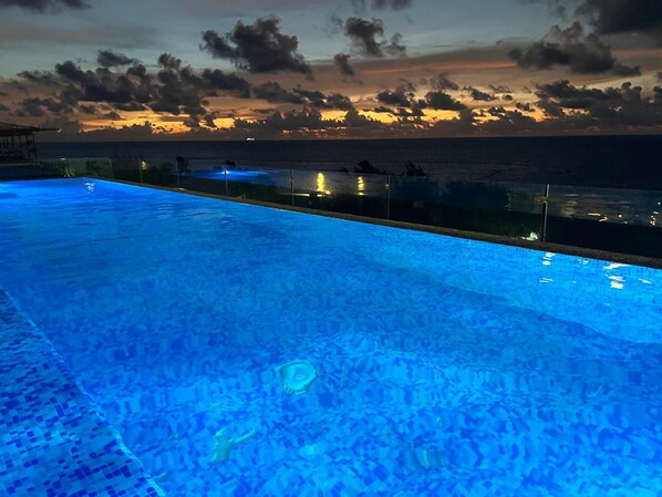 En pool med havudsigt og solnedgang.