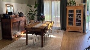 A dining area with a wooden table, chairs, a cabinet, and a potted plant. - Charming single-storey house (Évran)