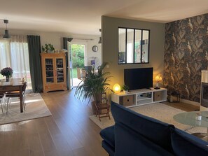 A living room with a TV, sofa, and a dining area with a table and chairs. - Charming one-story house (Évran)