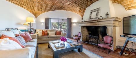 Una sala de estar con chimenea, un conjunto de sofás, una mesa de centro y un televisor.