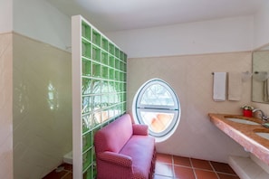 A bathroom with a tiled floor, a window, a sink, and a toilet.