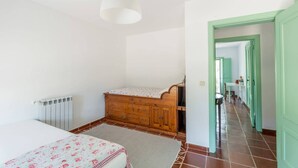 A bedroom with a bed, dresser, radiator, and a hallway leading to another room. - 188 - Quinta da Sobreda (Benavente)