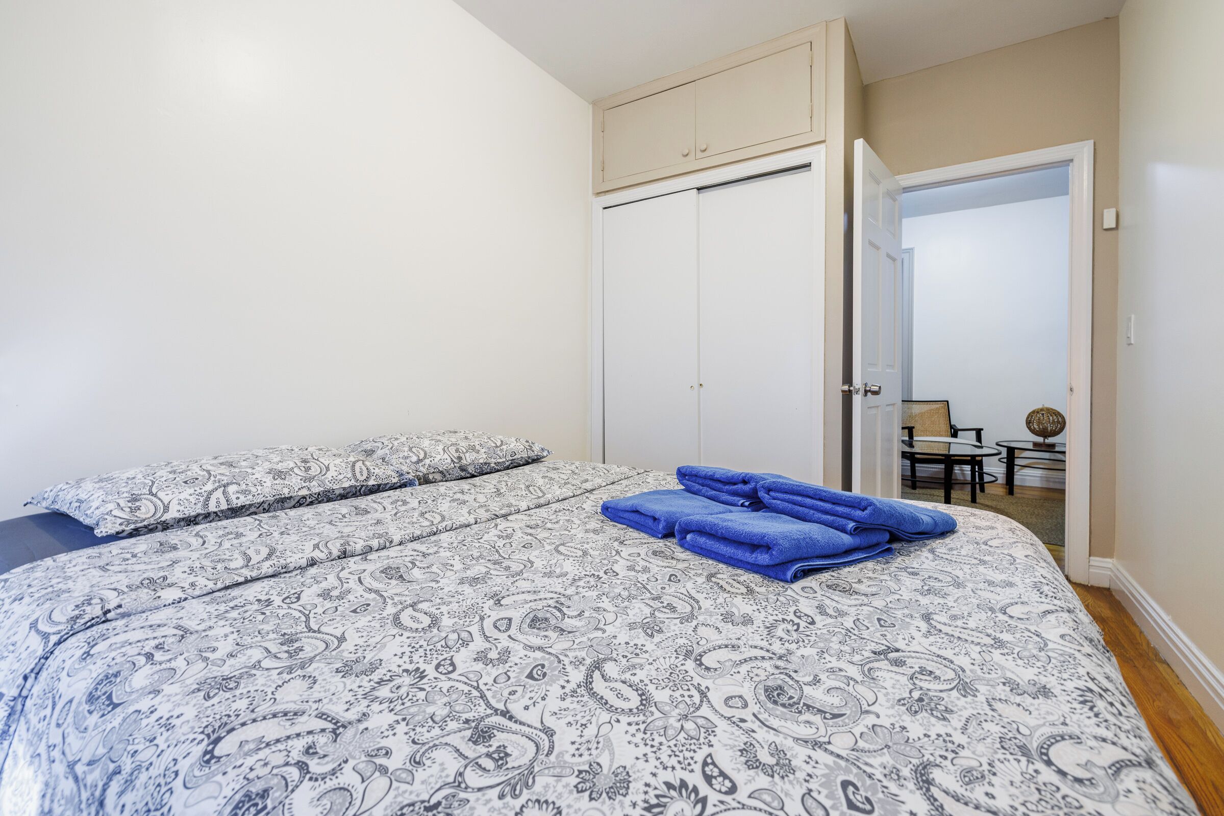 Une chambre à coucher comprenant un lit, une armoire et une petite table avec des chaises dans la pièce adjacente.