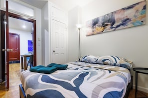 Ein Schlafzimmer mit einem Bett, einem Bild an der Wand und einem Schreibtisch mit Stuhl.