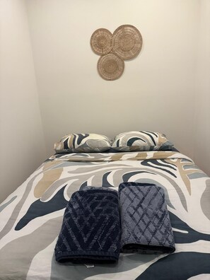 Ein Bett mit gemusterten Betttextilien und zwei gefalteten Decken.